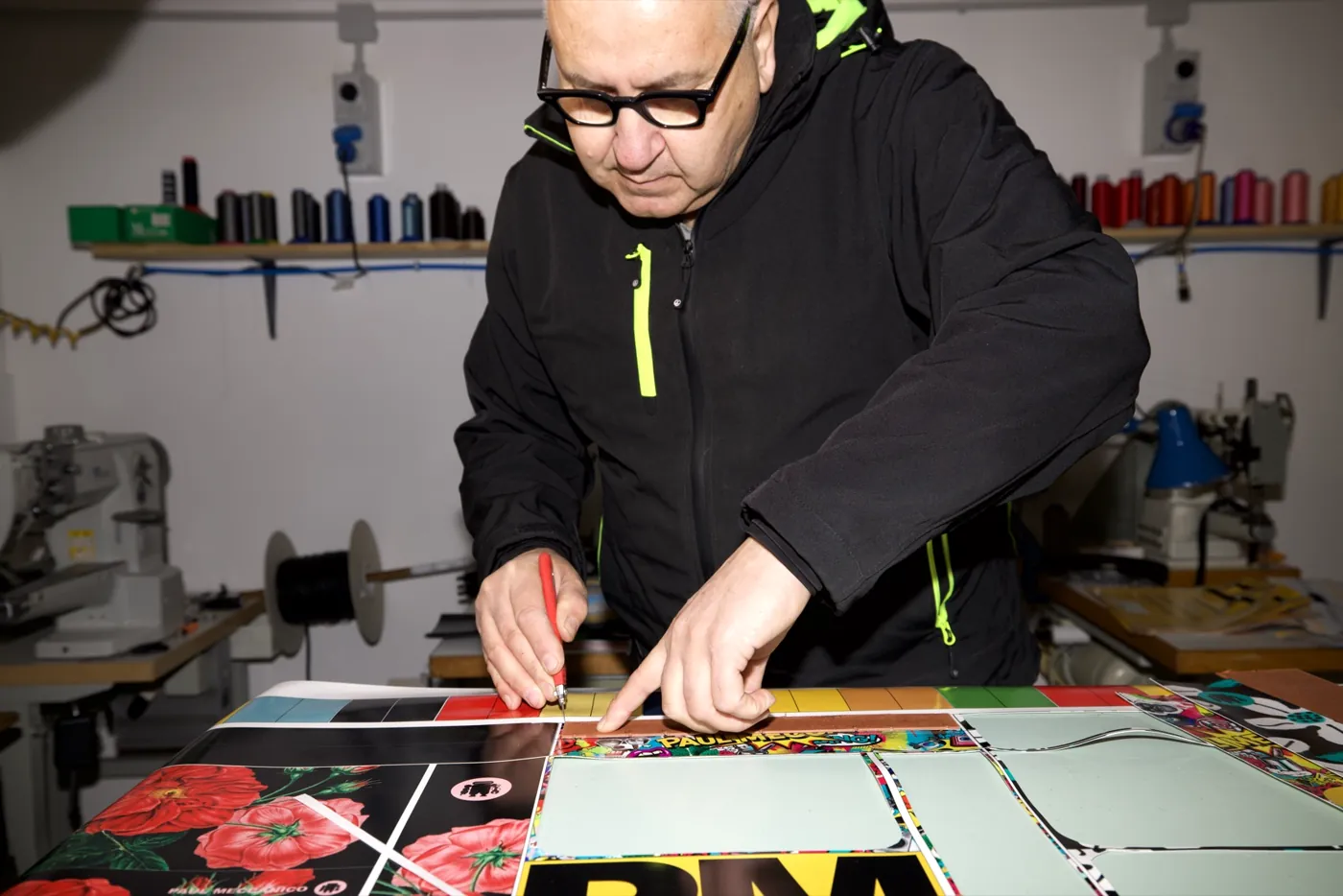 Paul au travail dans l’atelier de Paul Meccanico, découpant à la main du matériau imprimé